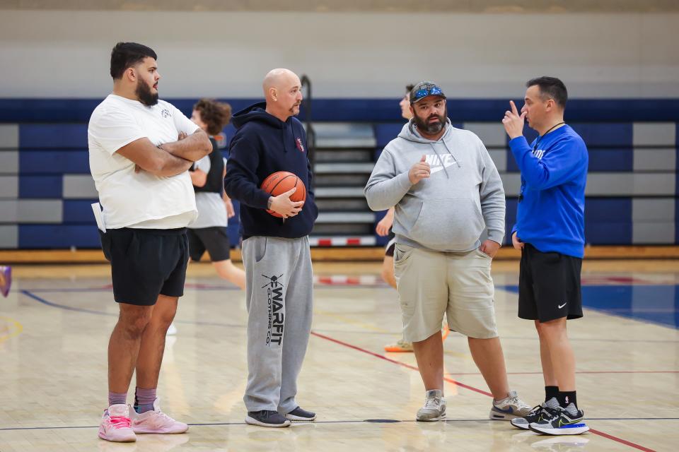 Winnacunnet High School boys basketball coach Jay McKenna, far right, talks with assistants, from left, Seth Provencher, Rusty Eaton and Matt McDonald during a break in Tuesday's practice.