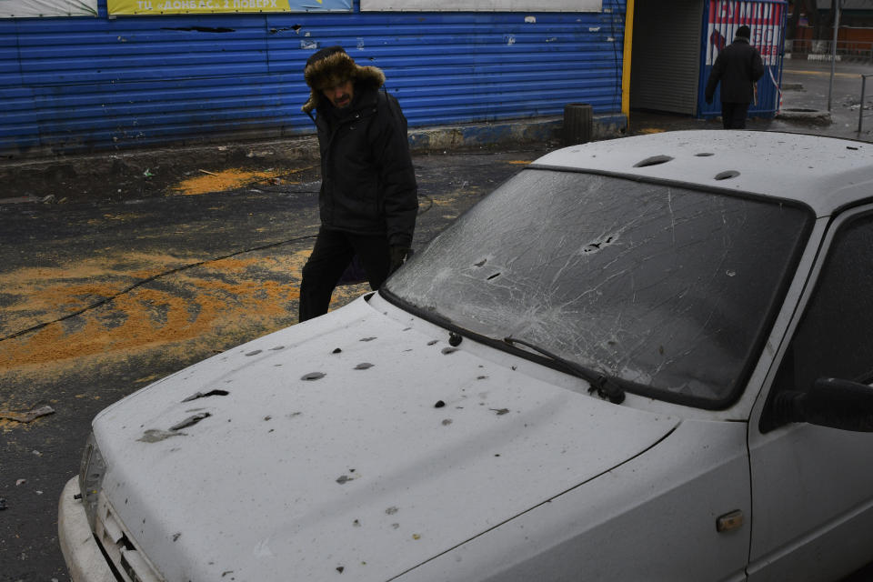 A man passes by a car damaged following Wednesday's Russian shelling, in Kurakhove, Donetsk region, Ukraine, Thursday, Dec. 8, 2022. (AP Photo/Andriy Andriyenko)