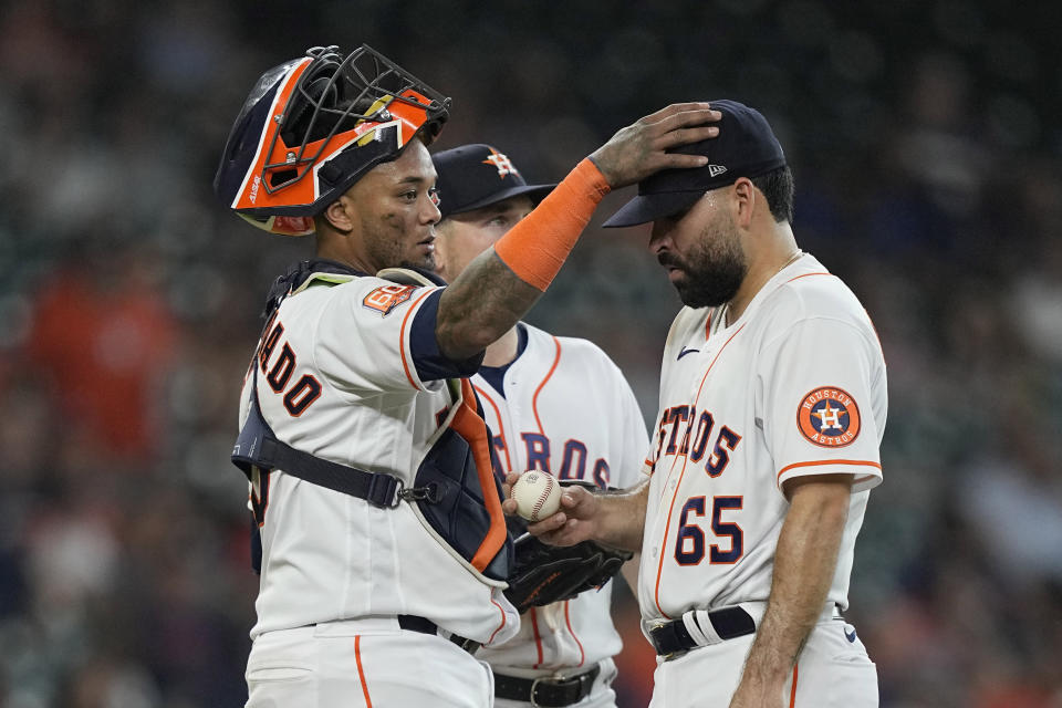 Houston Astros catcher Martin Maldonado, left, pats starting pitcher Jose Urquidy (65) on the head as manager Dusty Baker Jr. makes his way to the mound to pull Urquidy from the baseball game during the fifth inning against the Seattle Mariners Wednesday, June 8, 2022, in Houston. (AP Photo/David J. Phillip)