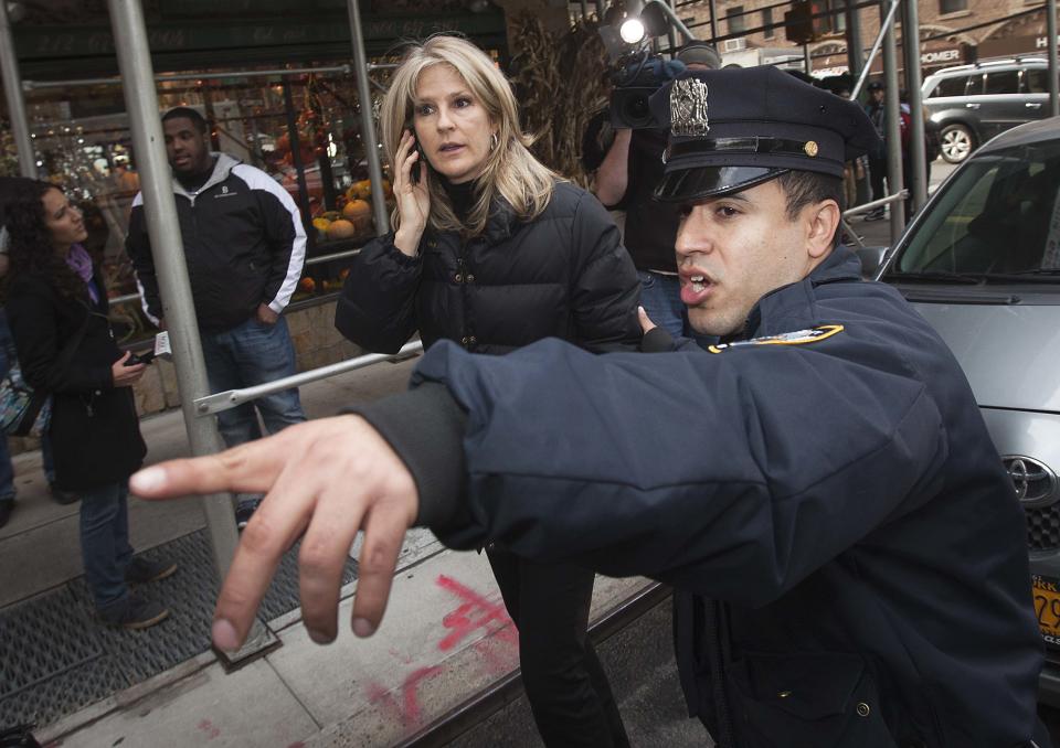 A police officer directs Linda Schmidt of FOX TV away for questioning in regards to what Hilaria Thomas, wife of Alec Baldwin, said was an altercation involving her and Schmidt, outside his apartment in New York