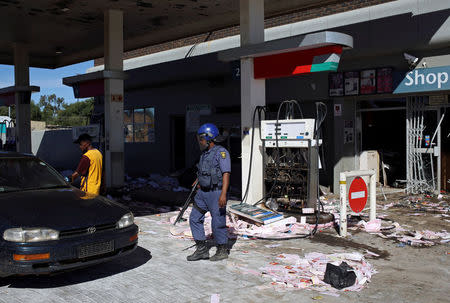 Police officer stands guard after a filling station was looted by protesters in Mahikeng, North West Province, South Africa, April 20, 2018. REUTERS/Siphiwe Sibeko