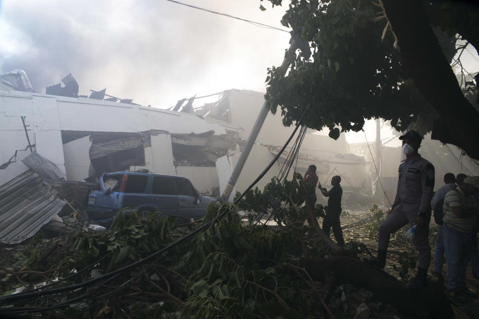 Residents make photos of the damaged caused by an explosion at the Polyplas plant in the Villas Agricolas neighborhood in Santo Domingo, Dominican Republic, Wednesday, Dec. 5, 2018. The mayor told reporters the fire began when a boiler exploded early Wednesday afternoon at the plastics company. Authorities say several people have died and dozens are injured. (AP Photo/Tatiana Fernandez)