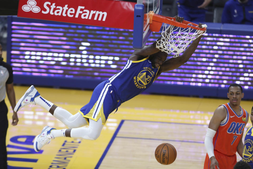 Golden State Warriors' Draymond Green hangs from the rim after scoring against Oklahoma City Thunder's Darius Bazley during the first half of an NBA basketball game in San Francisco, Saturday, May 8, 2021. (AP Photo/Jed Jacobsohn)