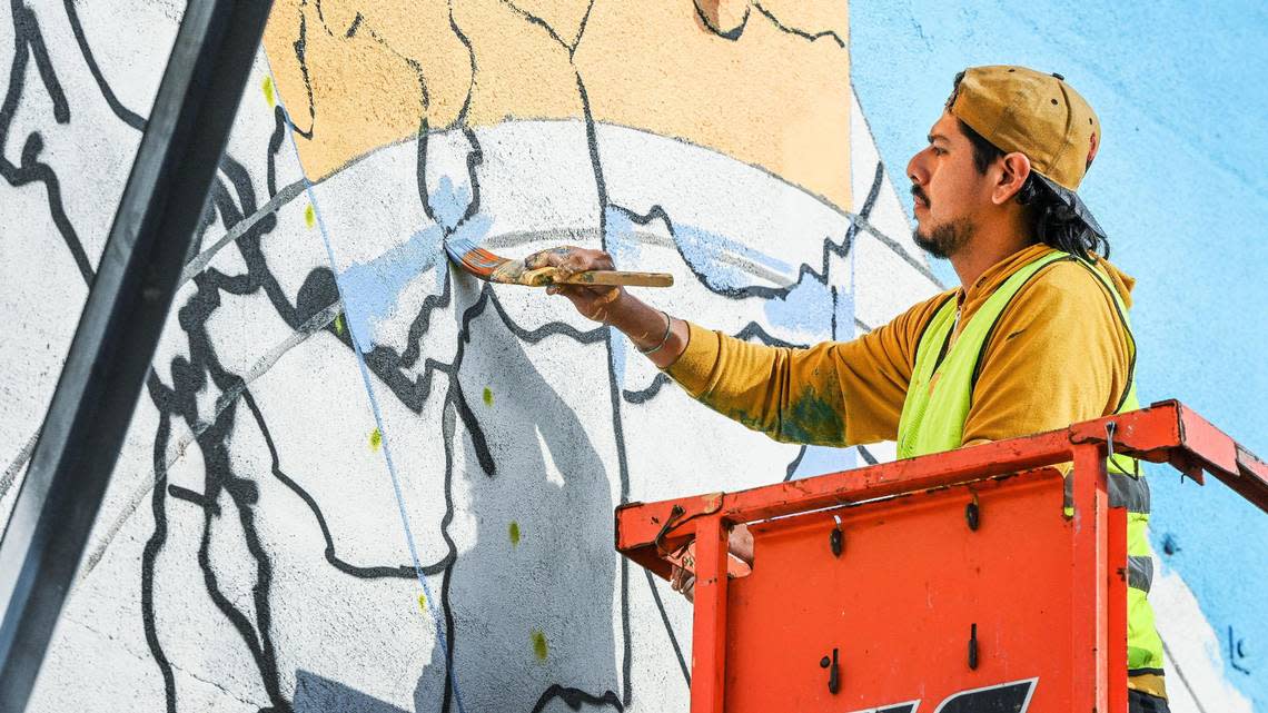 Fresno muralist Mauro Carrera works on a mural on a historical Chinatown building on China Alley in downtown Fresno on Thursday, Dec. 8, 2022. The project is in conjunction with the Fresno Arts Council and the California High-Speed Rail Authority.