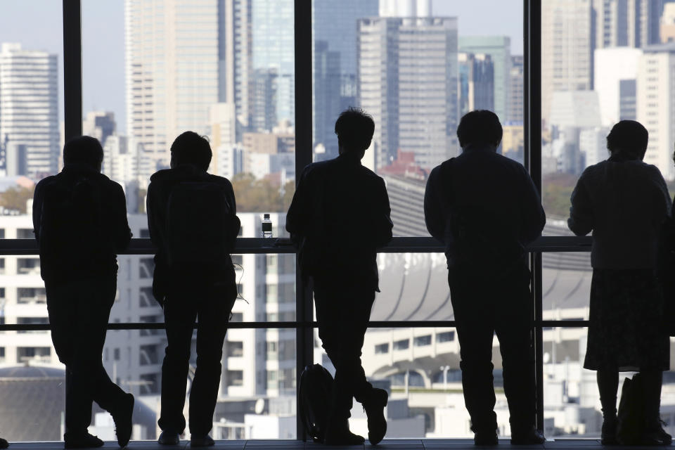 People stand by the windows in a high-rise commercial building in Tokyo, Thursday, Nov. 14, 2019. Japan’s economy grew at a modest annual pace of 0.2% in July-September, supported by consumer purchases ahead of a tax hike, the government said Thursday. (AP Photo/Koji Sasahara)