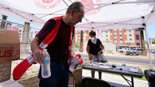 PHOTO: Salvation Army volunteer Cleon Streitmatter hands out water bottles at a Salvation Army heat relief station as temperatures hit 114-degrees, July 11, 2022, in Phoenix. (Ross D. Franklin/AP)