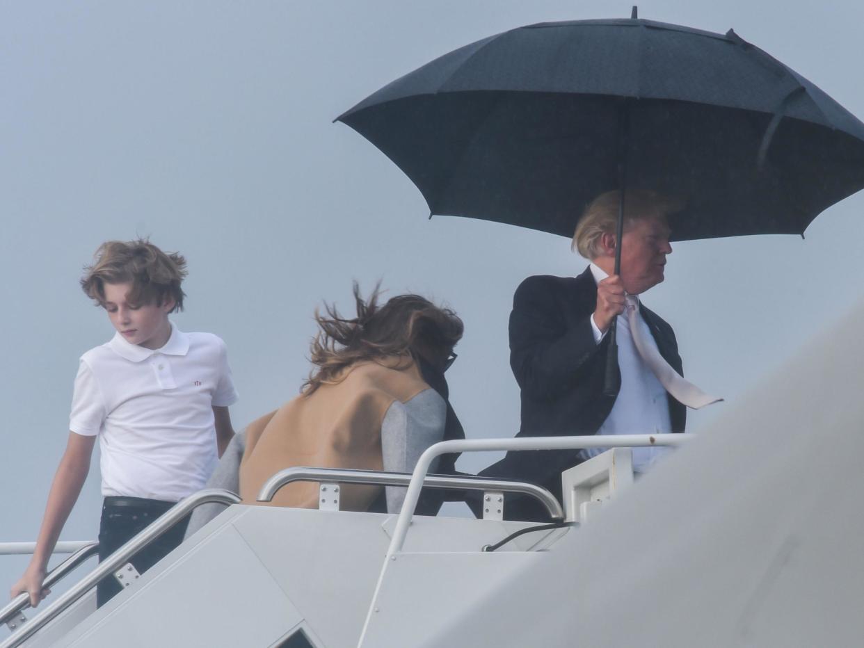 US President Donald Trump holds an umbrella as he waits for his son Barron and wife Melania to board Air Force One at Palm Beach International Airport in West Palm Beach, Florida: NICHOLAS KAMM/AFP/Getty Images