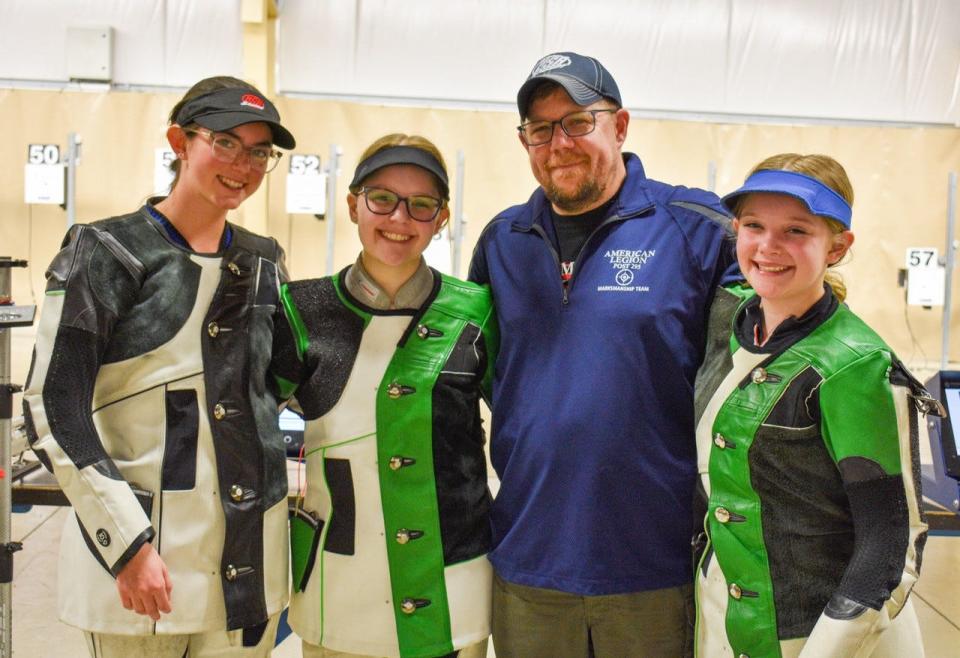 Head Coach Matt Muzik has trained his marksmanship team, which includes his two daughters, to skill levels that qualified them for the Junior Olympics. Here, he stands with, from left, Hailey Singleton, Claudia Muzik and Delilah Muzik.