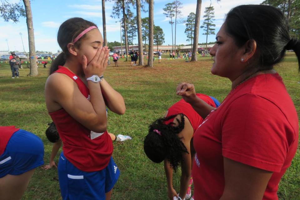 Coach Paula Montoya talks with Kenairis Villanueva just before the start of the regional cross country meet in George County on Oct. 26, 2021.