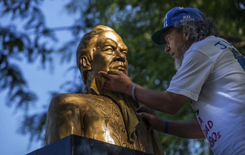 MAYWOOD, CA-JULY 16, 2022: Alex Vanegas, 65, a migrant from Nicaragua, cleans a bust of Nicaraguan poet Ruben Dario, at Maywood Riverfront Park in Maywood. He has been working to clean and renovate the bust since it's been getting deteriorated with rust over the last decade. The Nicaraguan American Opportunity Foundation is an organization that offers support and refuge to migrants from Nicaragua, and also works as a cultural space for those Nicaraguans living in Los Angeles. Vanegas, who is one of those migrants, is part of the organization. He fled the country after being arrested multiple times, spending months in prison and house arrest, and is learning to assimilate to Los Angeles. (Mel Melcon / Los Angeles Times)