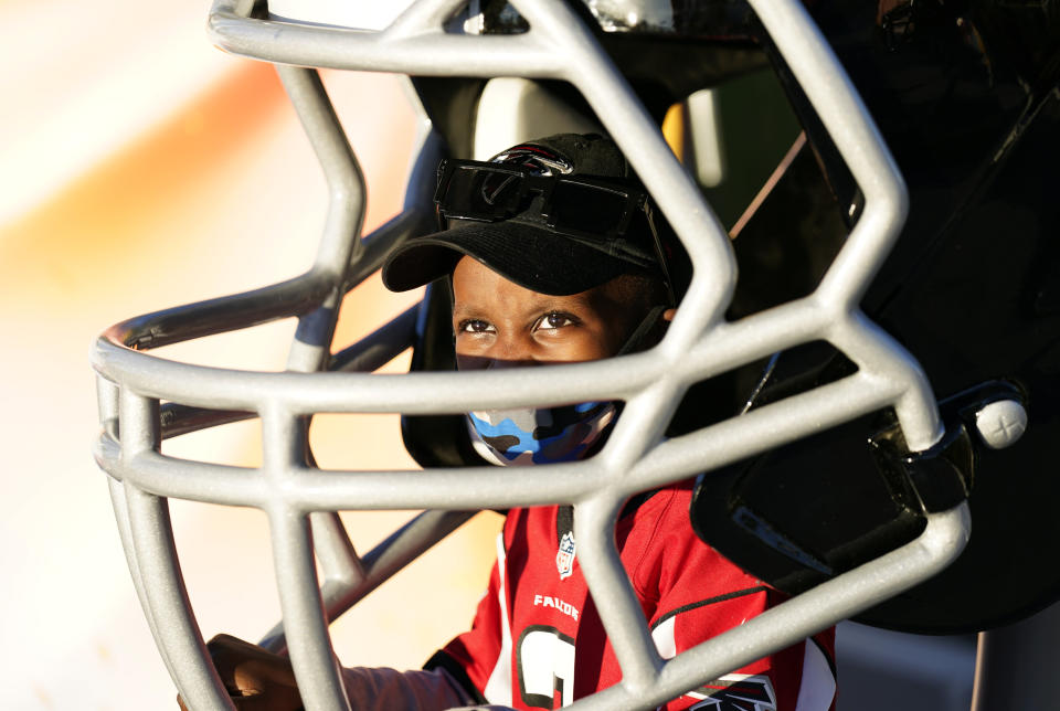 Isaiah Sheppard, 7, sits inside an oversized football helmet at the NFL Experience for Super Bowl LV Friday, Jan. 29, 2021, in Tampa, Fla. (AP Photo/David J. Phillip)