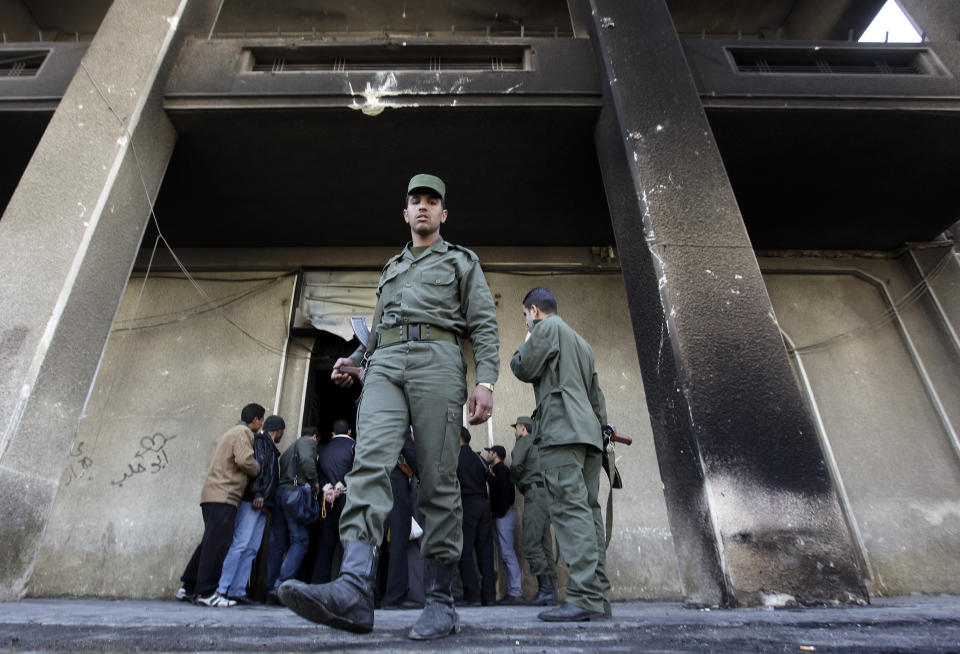 FILE - In this March 21, 2011, file photo, a Syrian soldier steps out of the burned courthouse that was set on fire by anti-government protesters in the southern city of Daraa, Syria. In March 2011, Daraa became the first city to explode against the rule of Syrian President Bashar Assad. (AP Photo/Hussein Malla, File)