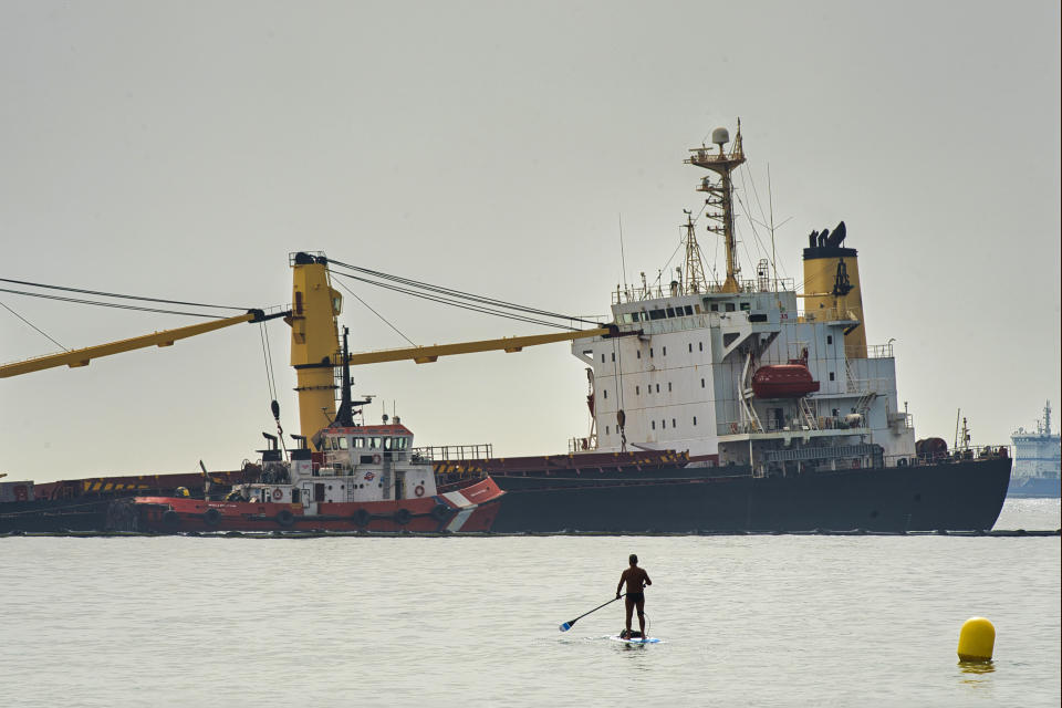 A man approaches with his paddle surf board to get a closer look at the Tuvalu-registered OS 35 cargo ship lying on the seabed, offshore Gibraltar, Tuesday, 30 Aug. 2022. Gibraltar authorities say they have beached a cargo ship to prevent it from sinking after it collided with a liquid natural gas carrier early Tuesday in the bay of Gibraltar. (AP Photo/Marcos Moreno)