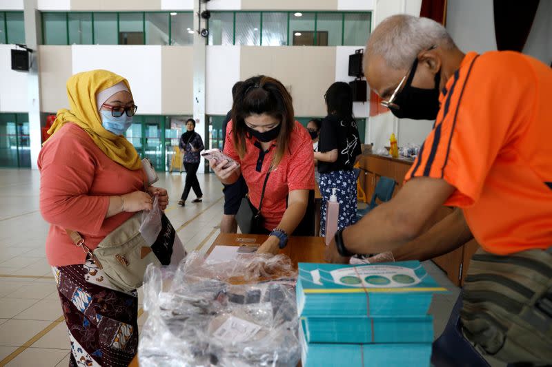 Residents receive free reusable masks distributed by the government at a community center, as stricter measures are announced to combat the outbreak of the coronavirus disease (COVID-19) in Singapore