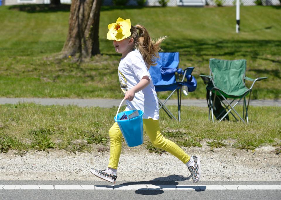 Danika Douglas runs along the parade route helping to pass out tomato seeds. She was with the Brewster Parent Teacher Organization who had a group walking during the 2022 Brewster in Bloom Town Parade handing out packets of seeds.