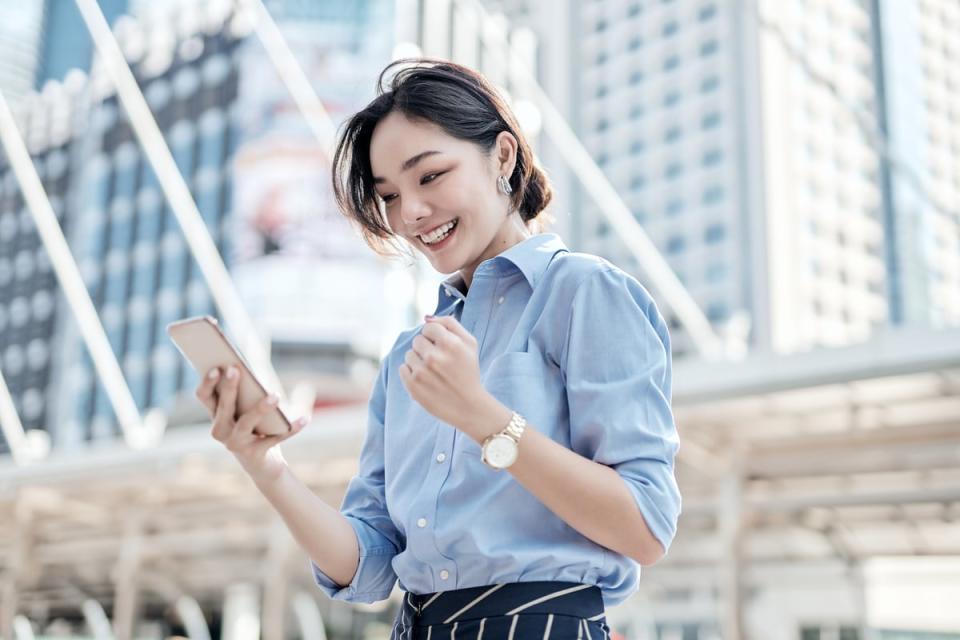 A person clenches his fist and smiles while looking at his cell phone.