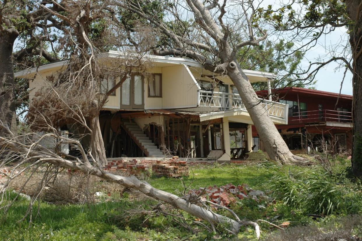 Wind damaged home with fallen trees.