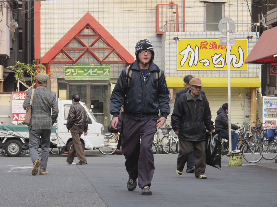 In this Sunday, March 16, 2014 photo, Japanese film director Shingo Ota walks in Kamagasaki, Osaka, western Japan, during his visit for the screening of his film "Fragile." Japan’s biggest slum, Kamagasaki, is visible just blocks from bustling restaurants and shops in Osaka, the country’s second-largest city. But it cannot be found on official maps. Nor did it appear in the recent Osaka Asian Film Festival, after Ota pulled it, accusing city organizers of censorship. Osaka officials asked Ota to remove scenes and lingo that identify the slum, on the grounds that it was insensitive to residents. “To me, what they were asking was a cover-up attempt to make this place non-existent,” he said in a recent interview. (AP Photo/Mari Yamaguchi)