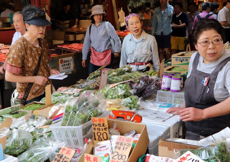 Shoppers check vegetables at a food market in Tokyo on May 20, 2015