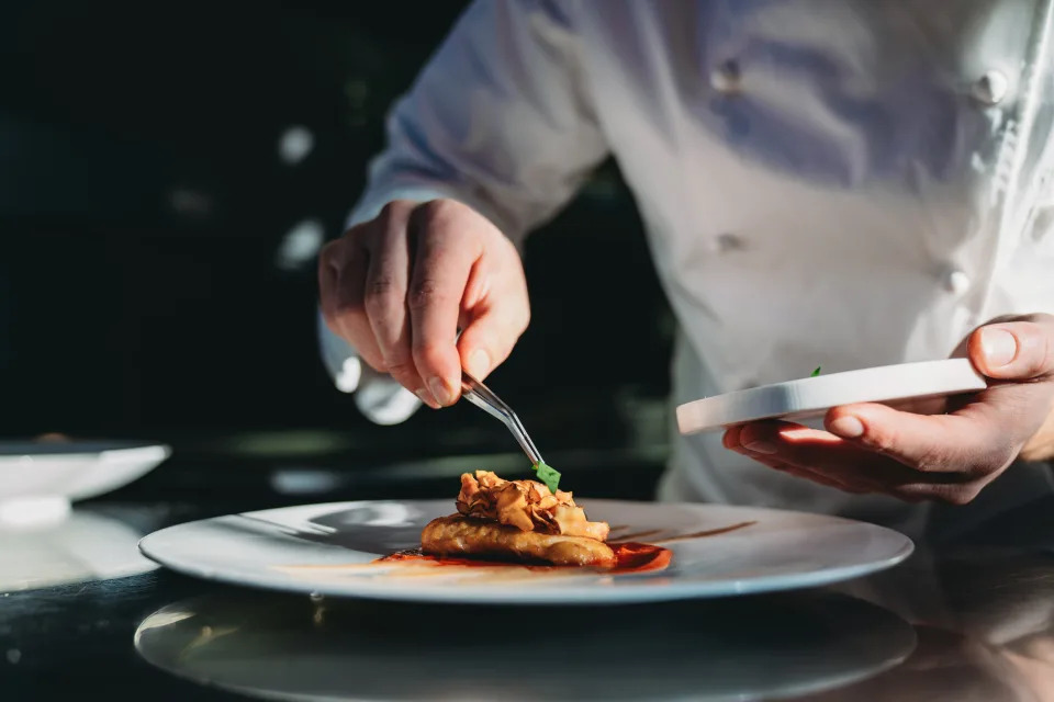 Chef meticulously garnishing a dish on a plate