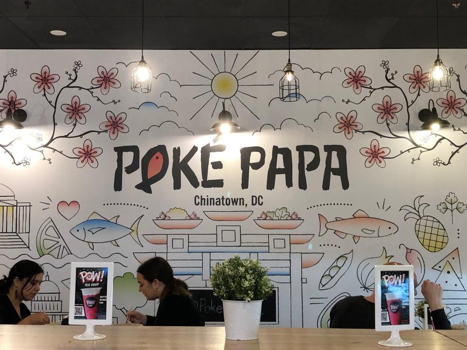 A mural on the wall inside Poke Papa features the sun, cherry blossoms, fish and fruit