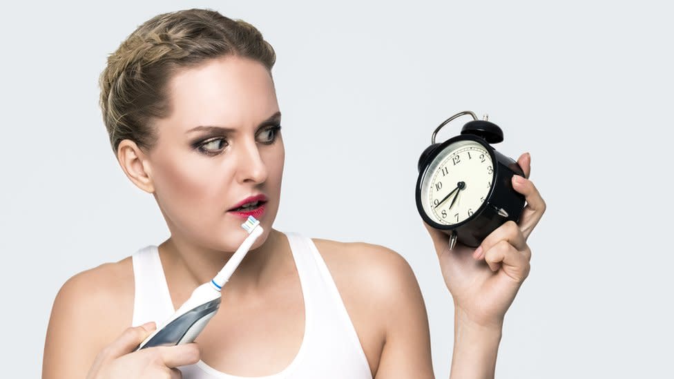 Mujer con un reloj lavándose los dientes.