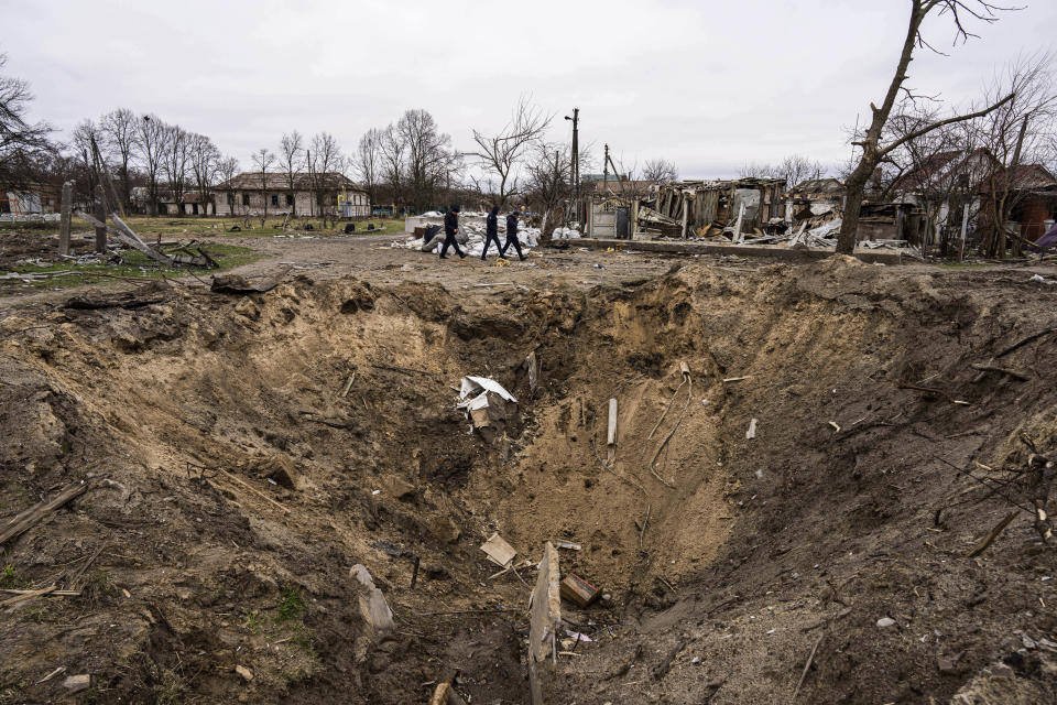 People walk past a crater from an explosion in Chernihiv, Ukraine, Wednesday, April 13, 2022. (AP Photo/Evgeniy Maloletka)