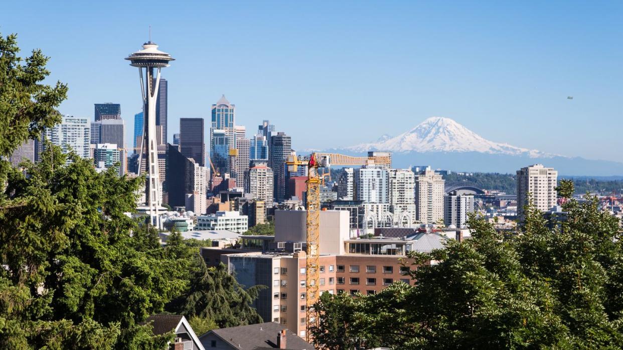 a classic view of seattle downtown district with the famous space needle tower and the mount rainier snow covered mountain in the background in washington state, usa