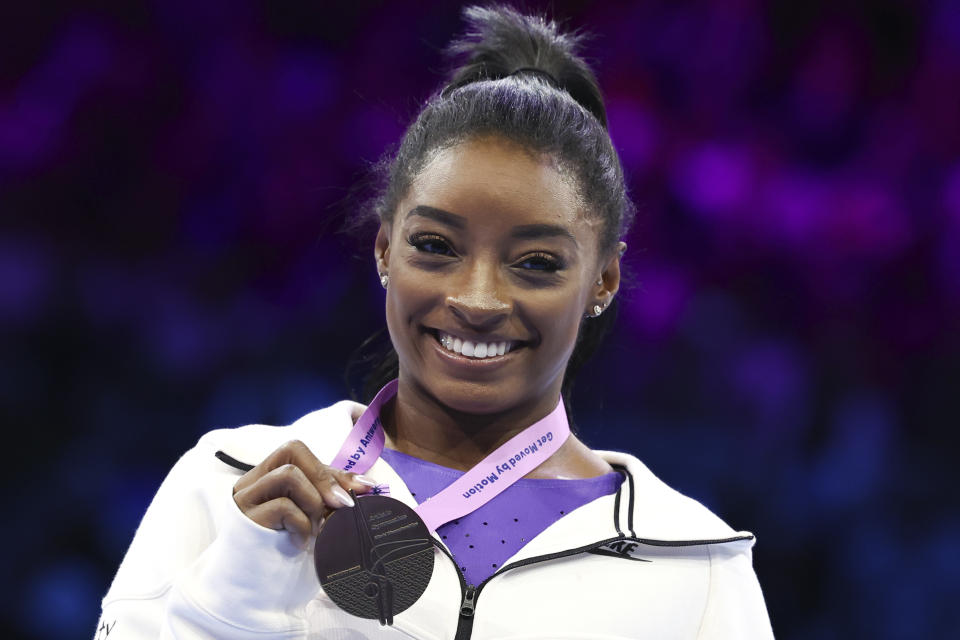 United States' Simone Biles shows her gold medal on the beam during the apparatus finals at the Artistic Gymnastics World Championships in Antwerp, Belgium, Sunday, Oct. 8, 2023. (AP Photo/Geert vanden Wijngaert)