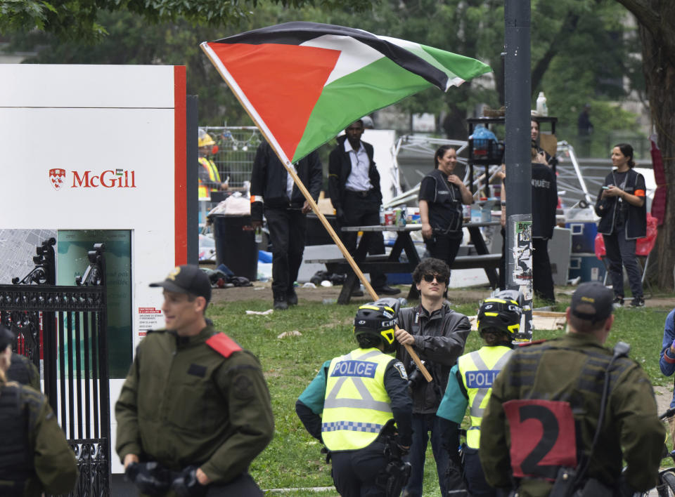 A protester waves a Palestinian flag as private security workers dismantle the encampment on McGill University campus Wednesday, July 10, 2024, in Montreal. (Ryan Remiorz/The Canadian Press via AP)