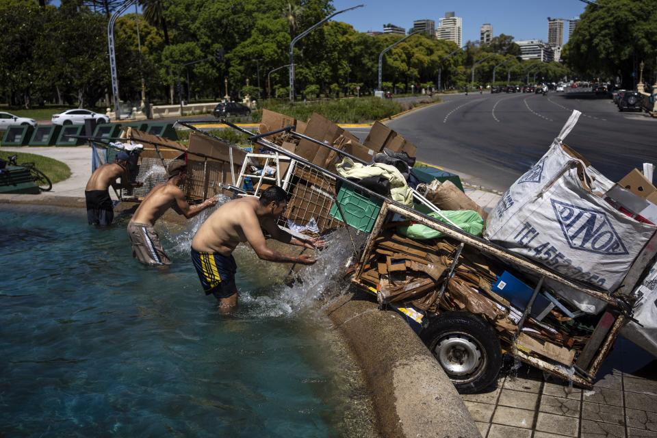 "Cartoneros" mojan con agua el cartón reciclado recolectado antes de pesarlo en un centro de reciclado, mientras se refrescan en una fuente en Buenos Aires, Argentina, el 11 de diciembre de 2023. La segunda mayor economía de Sudamérica sufre una inflación anual del 143% y cuatro de cada 10 argentinos han caído bajo el umbral de la pobreza. (AP Foto/Rodrigo Abd)