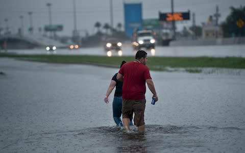 People walk through flooded streets during the aftermath of Hurricane Harvey - Credit: BRENDAN SMIALOWSKI/AFP/Getty