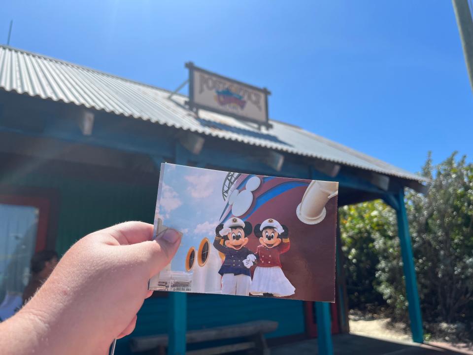 Holding Disney post card in front of Post office at Castaway Cay