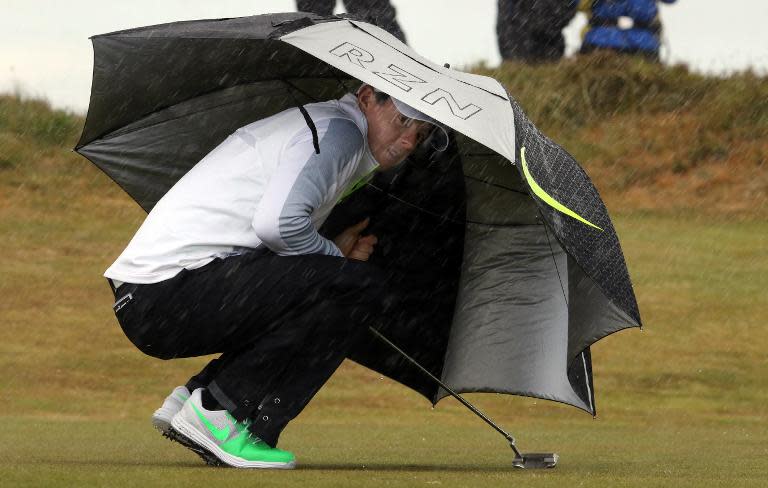 Northern Irish golfer Rory McIlroy shelters from rain and wind on the 6th tee on the second day of the Irish Open at the Royal County Down Golf Club in Newcastle in Northern Ireland on May 29, 2015