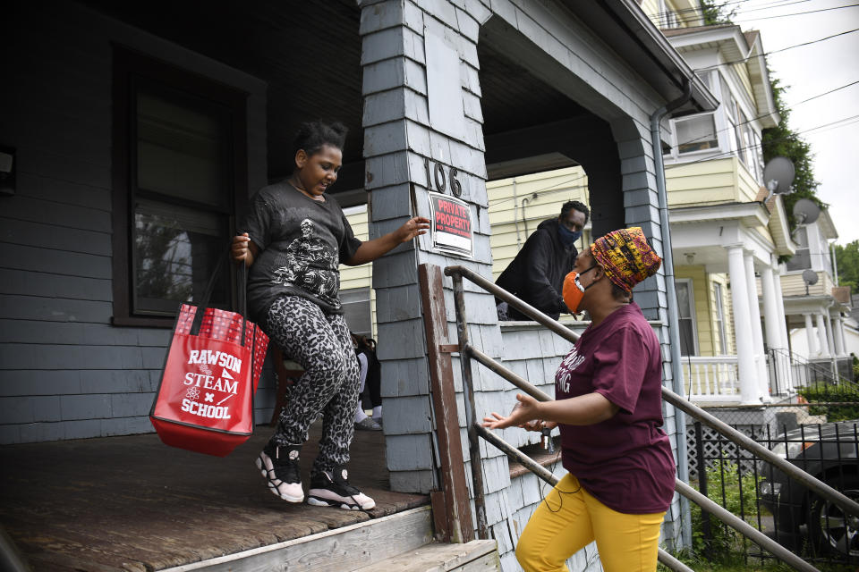 In this Friday, June 5, 2020 photo, third-grade student Nevaeh Bernard runs in excitement toward Sarah J. Rawson Elementary School Principal Dr. Tayarisha Batchelor, during a visit from Dr. Stone to Nevaeh's home in Hartford, Conn. (AP Photo/Jessica Hill)