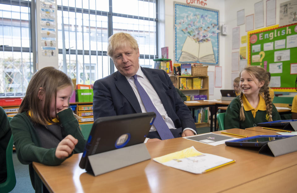 Britain's Prime Minister Boris Johnson, centre, reacts with pupils during a visit to Middleton Primary School in Milton Keynes, England, Friday Oct. 25, 2019. European Union ambassadors agreed Friday that the bloc should grant Britain’s request for another extension to the Brexit deadline but have not yet figured out how long that delay should be. (Paul Grover/Pool via AP)