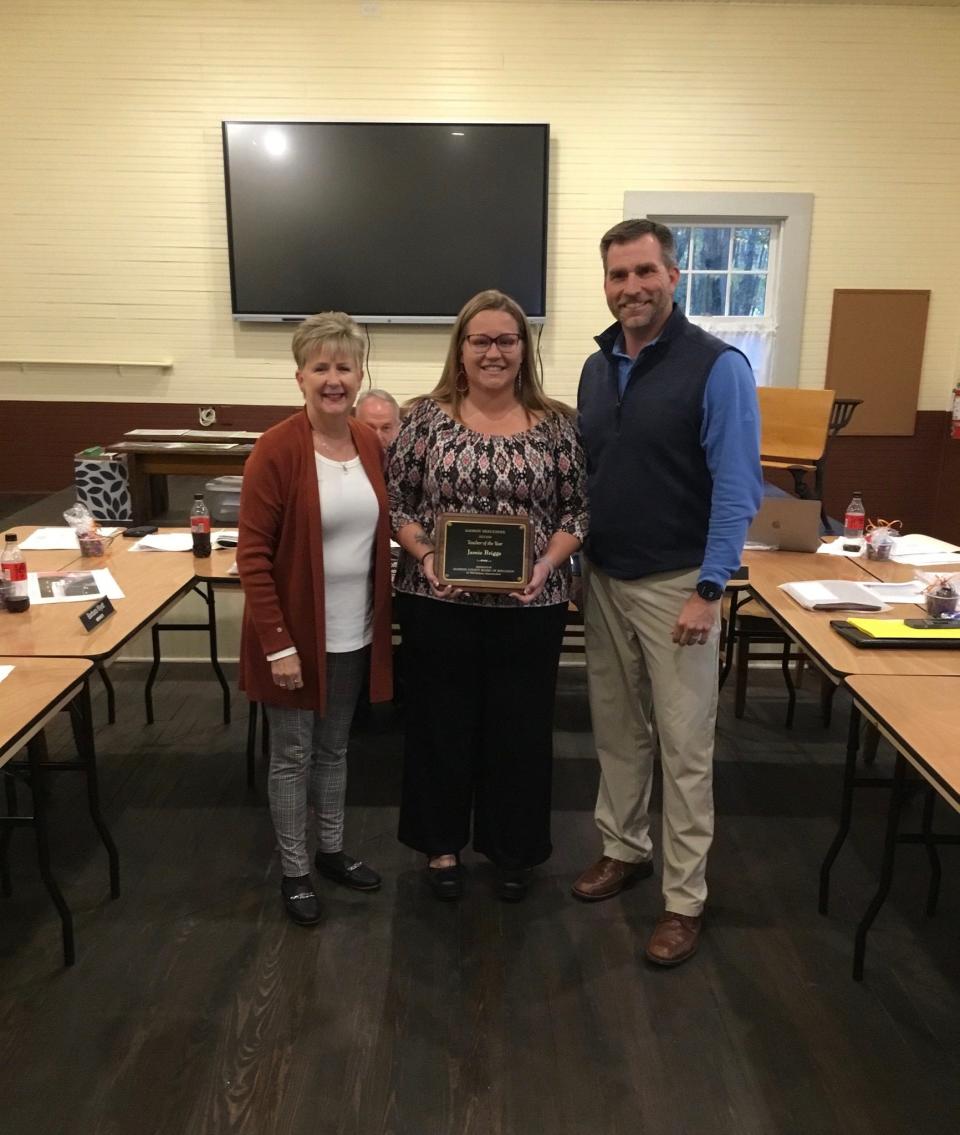 Madison County Board of Education Chair Karen Blevins and Madison High Principal Kevin Huskins present Jamie Briggs a plaque honoring her as 2023 Teacher of the Year.