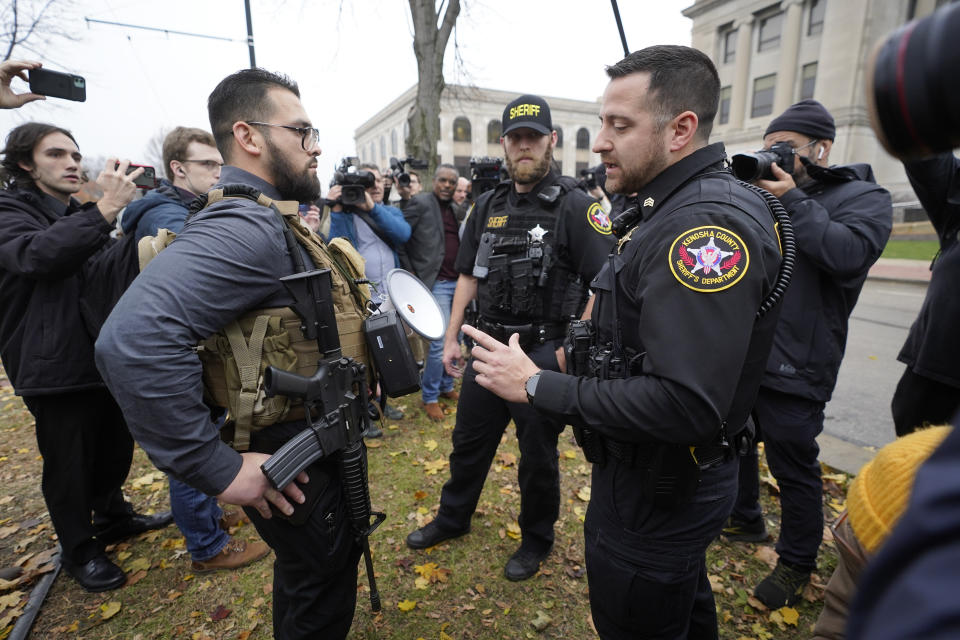 Kenosha County Sheriffs Department officers question a protester carrying a rifle outside the Kenosha County Courthouse, Wednesday, Nov. 17, 2021 in Kenosha, Wis., during the Kyle Rittenhouse murder trial. Rittenhouse is accused of killing two people and wounding a third during a protest over police brutality in Kenosha, last year. (AP Photo/Paul Sancya)