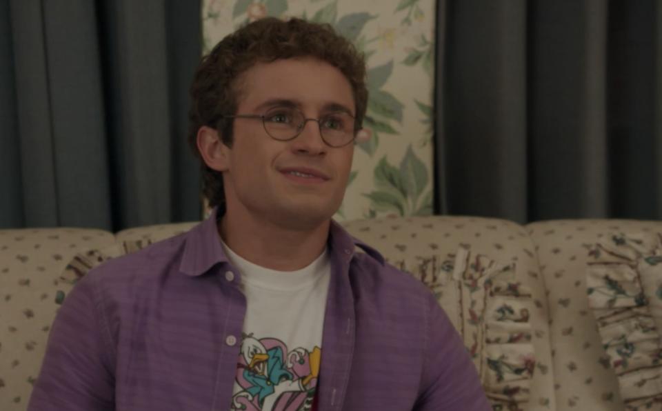 Adam Goldberg's character gives a half-hearted grin while sitting on his living room couch in 'The Goldbergs'