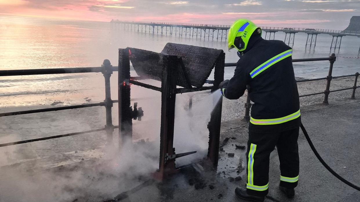 Firefighter extinguishing bin fire on Saltburn promenade