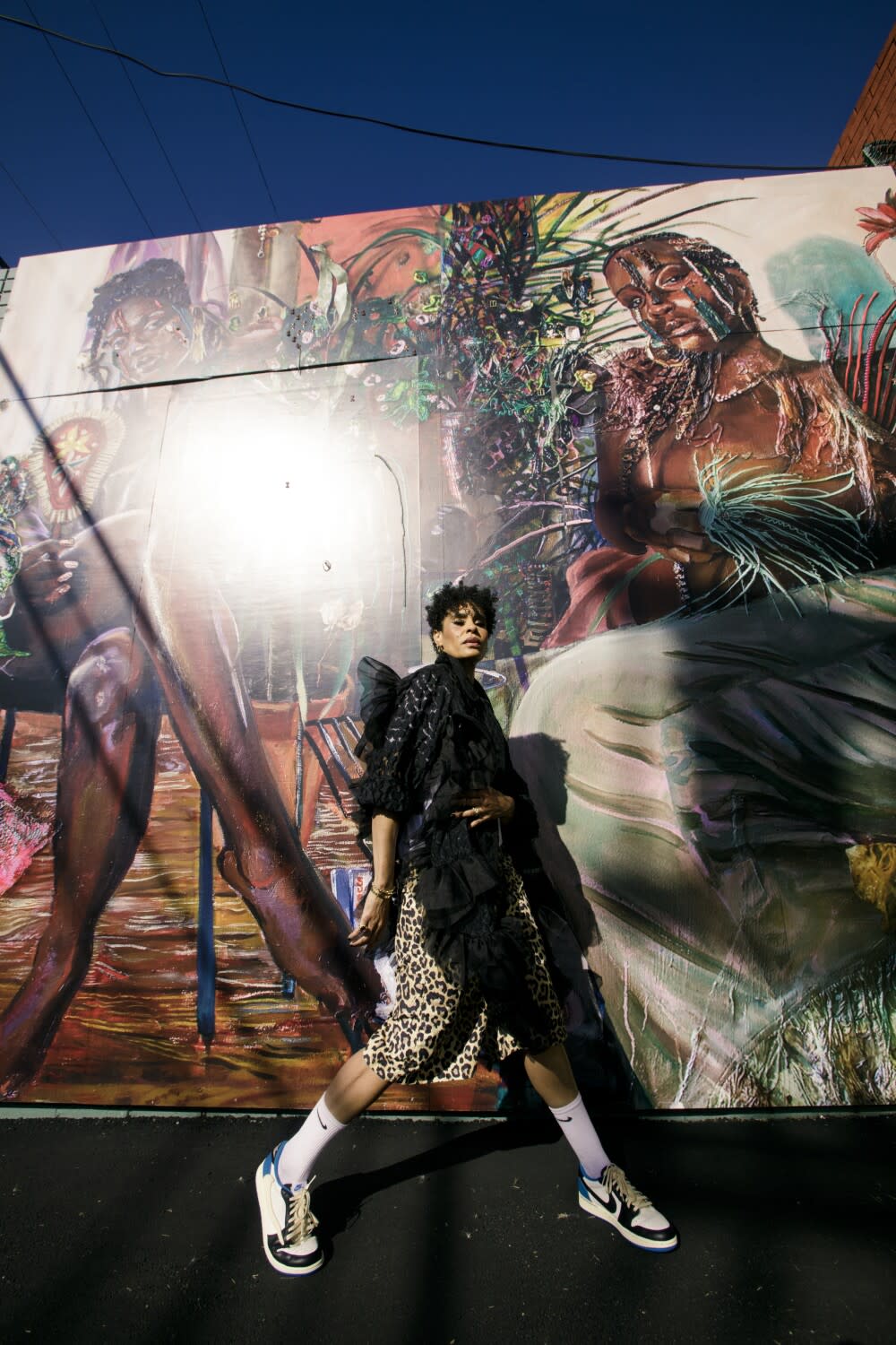 Angela Manuel-Davis poses in front of Gisela McDaniel's murals outside