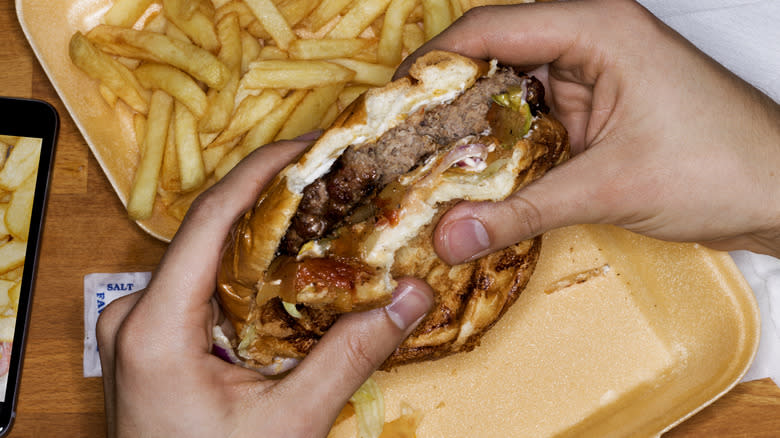 holding a burger and fries