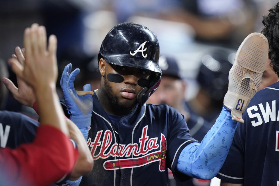 El venezolano Ronald Acuña Jr., de los Bravos de Atlanta, es felicitado por sus compañeros, tras anotar en un sencillo de Matt Olson ante los Marlins de Miami, en el segundo juego de una doble tanda disputada el sábado 13 de agosto de 2022 (AP foto/Wilfredo Lee)