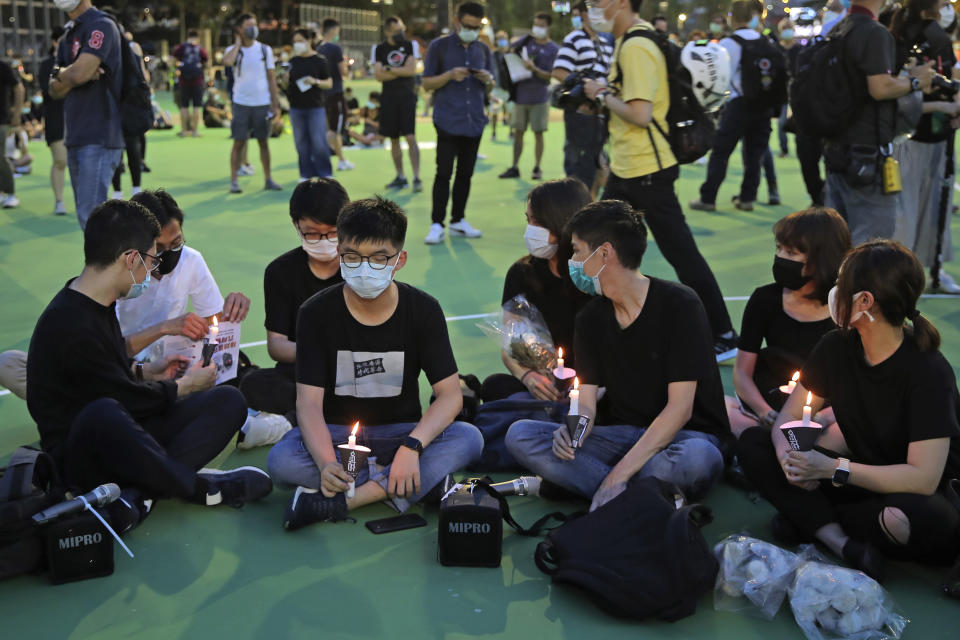 In this June 4, 2020 photo, Hong Kong democracy activist Joshua Wong, second left, holds candle as he joins others for a vigil to remember the victims of the 1989 Tiananmen Square Massacre at Victoria Park in Hong Kong. Wong will face an additional 10 months in jail for participating in an unauthorized Tiananmen vigil held last year to commemorate the 1989 crackdown on protesters in Beijing, as Hong Kong authorities continue tightening control over dissent in the city. (AP Photo/Kin Cheung)