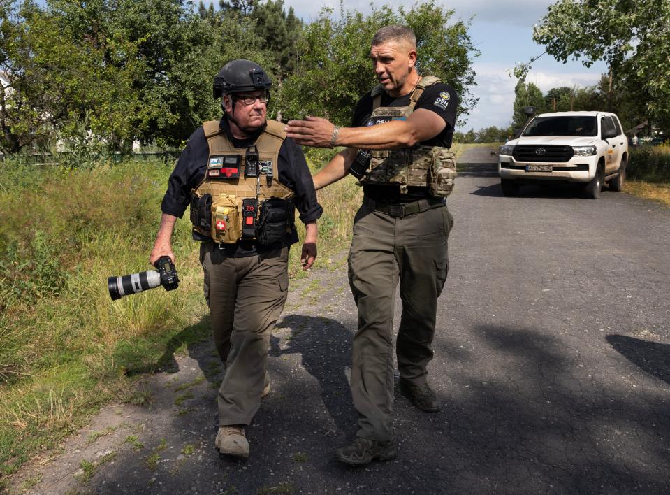 American billionaire Howard Buffet (L) receives advice from his Ukrainian security while wearing body armor and a helmet on the frontlines on June 15, 2023, in Zolota Nyva, Donetsk district, Ukraine.