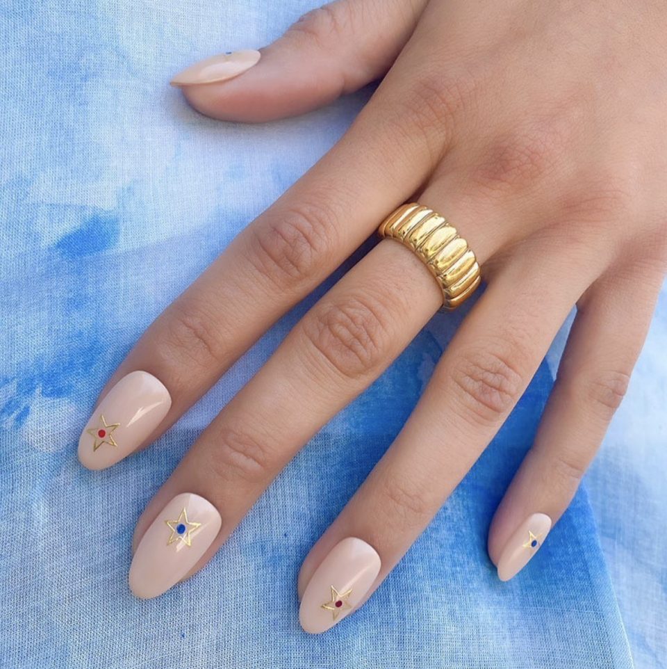 <p>Add dainty gold stars to a neutral manicure. It's perfect for a holiday <a href="https://www.goodhousekeeping.com/beauty/nails/g3720/wedding-nail-designs/" rel="nofollow noopener" target="_blank" data-ylk="slk:wedding;elm:context_link;itc:0;sec:content-canvas" class="link ">wedding</a> or backyard barbecue, alike. Place small red and blue dots in between the stars so that you'll look at home at the cookout. </p><p><a class="link " href="https://www.amazon.com/Stickers-Self-Adhesive-Metallic-Accessories-Decoration/dp/B08LT4SDPY/?tag=syn-yahoo-20&ascsubtag=%5Bartid%7C10055.g.1278%5Bsrc%7Cyahoo-us" rel="nofollow noopener" target="_blank" data-ylk="slk:SHOP GOLD NAIL JEWELRY;elm:context_link;itc:0;sec:content-canvas">SHOP GOLD NAIL JEWELRY</a></p>