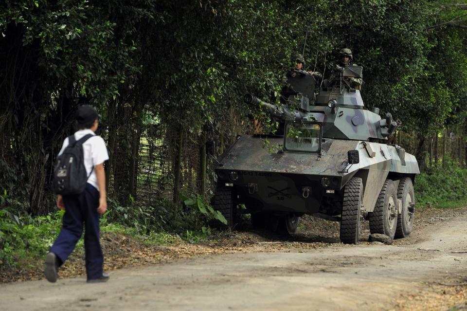 a schoolboy walks by a colombian army ee