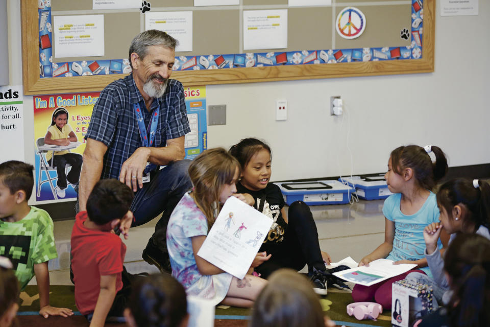 In this Sept. 19, 2019 photo, Gary Bass, digital literacy teacher at El Camino Real Academy in Santa Fe, New Mexico, works with one of his second grade classes. The Santa Fe educator is taking a one-month leave from his classroom to train English teachers in Kampot, Cambodia. (Luis Sanchez Saturno/Santa Fe New Mexican via AP)