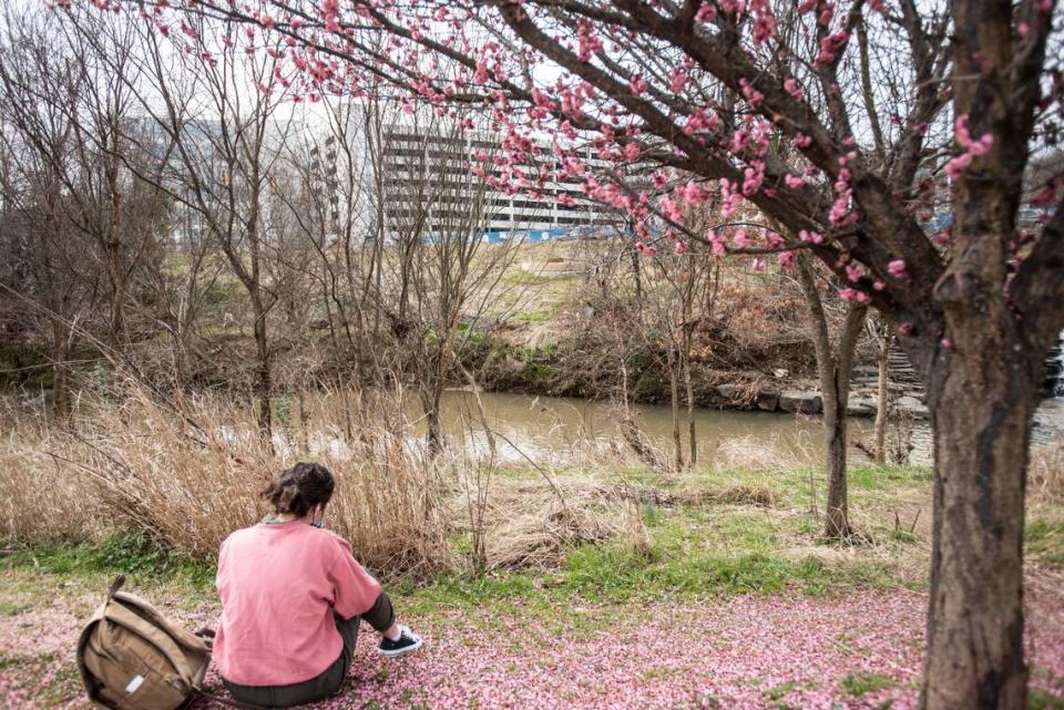 A woman sits by a Sugar Creek in Charlotte, NC, on Saturday, February 25, 2021.