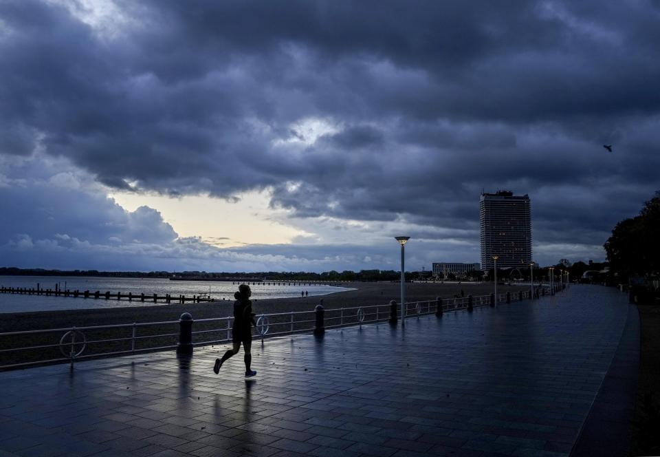 A woman runs on the promenade at the Baltic Sea in Travemuende, northern Germany, Thursday, Oct.21, 2021. Northern Germany was hit by storm and heavy rain falls. (AP Photo/Michael Probst)